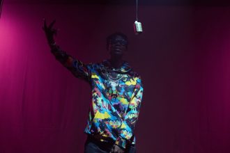 Artista de hip-hop se apresenta no palco diante de um microfone vintage.